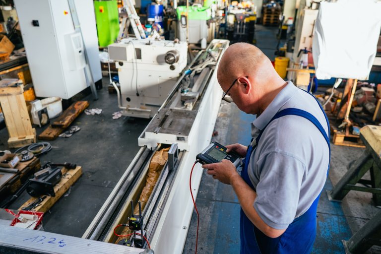Der Eigentümer prüft mit einem Messgerät die Ausrichtung einer Werkzeugmaschine in der Werkstatt, aufgenommen bei einem Maschinenbau Unternehmen in Aschersleben.