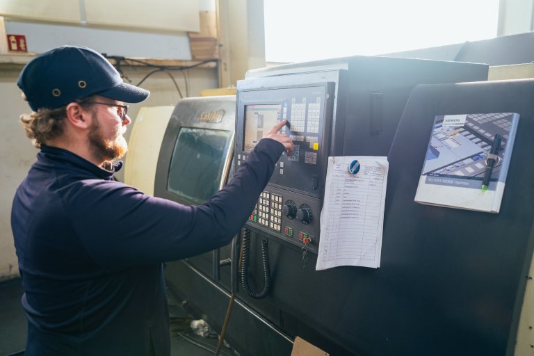 Ein Mitarbeiter bedient die CNC-Steuerung einer Werkzeugmaschine und gibt Einstellungen am Bedienfeld ein, aufgenommen bei einem Maschinenbau Unternehmen in Aschersleben.